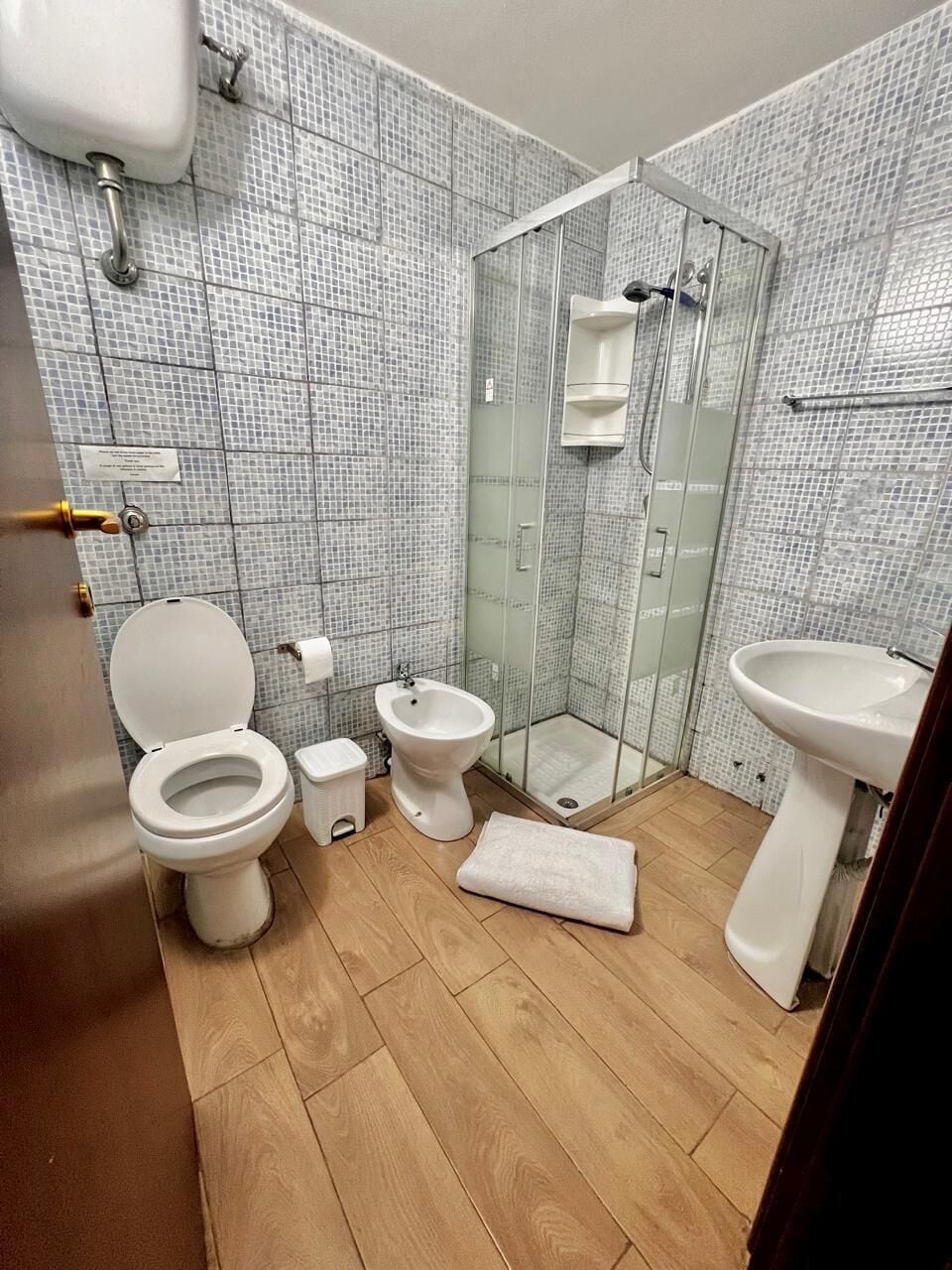A bathroom with a toilet, bidet, sink, and glass shower enclosure.