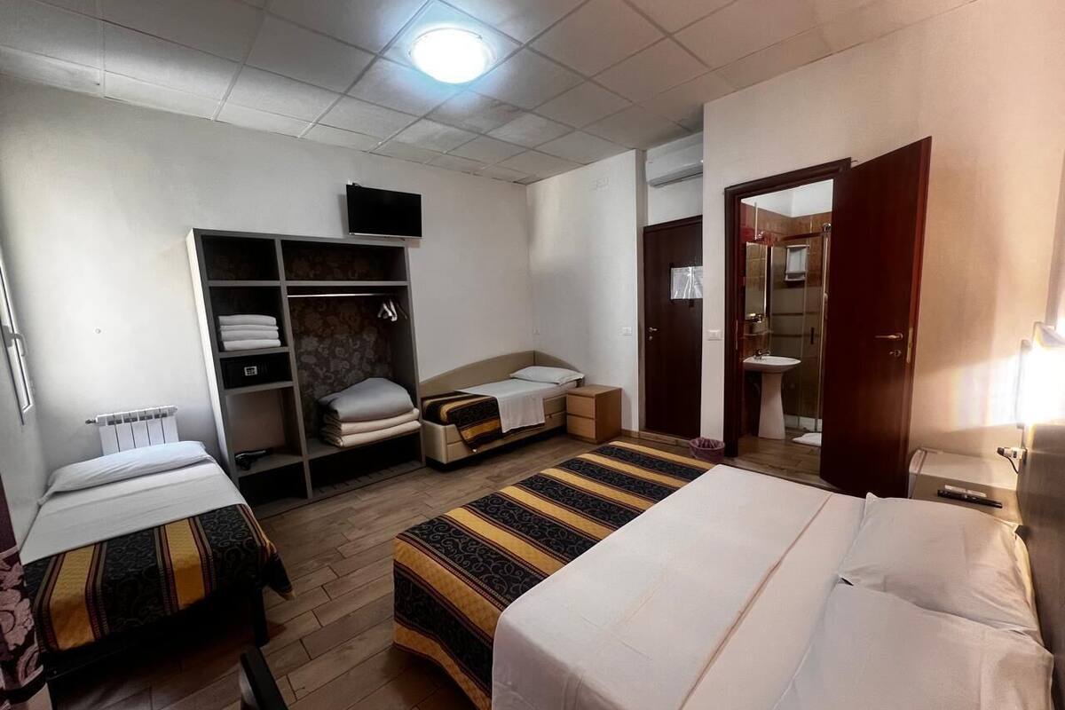 A hotel room with a bed, a wardrobe, a desk, and a bathroom.