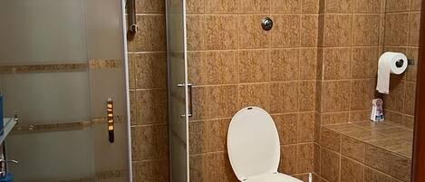 A bathroom with a glass-enclosed shower, a toilet, and two sinks.