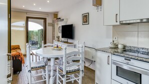 Eine moderne Küche mit weißen Schränken, einem eingebauten Ofen und einem Essbereich mit Tisch und Stühlen, alles in Weiß.