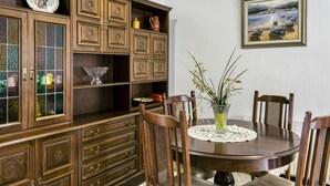 A dining room with a wooden cabinet, a table with chairs, and a vase with flowers.
