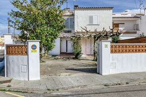 A residential building with a gated entrance, a small garden, and a tiled roof.