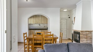 A dining area with a wooden table and chairs, a kitchen with wooden cabinets, and a fireplace. - Holiday Home 'Allegra' with Private Pool, Wi-Fi and Air Conditioning (L'Escala)