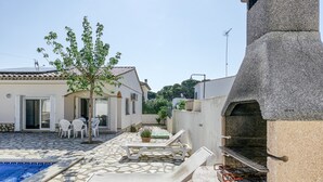 A pool area with lounge chairs, a barbecue grill, and a stone-tiled patio. - Holiday Home 'Allegra' with Private Pool, Wi-Fi and Air Conditioning (L'Escala)