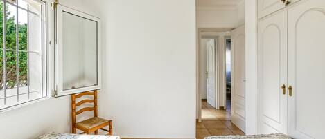 A bedroom with two beds, a wooden chair, a large mirror, and a wardrobe.