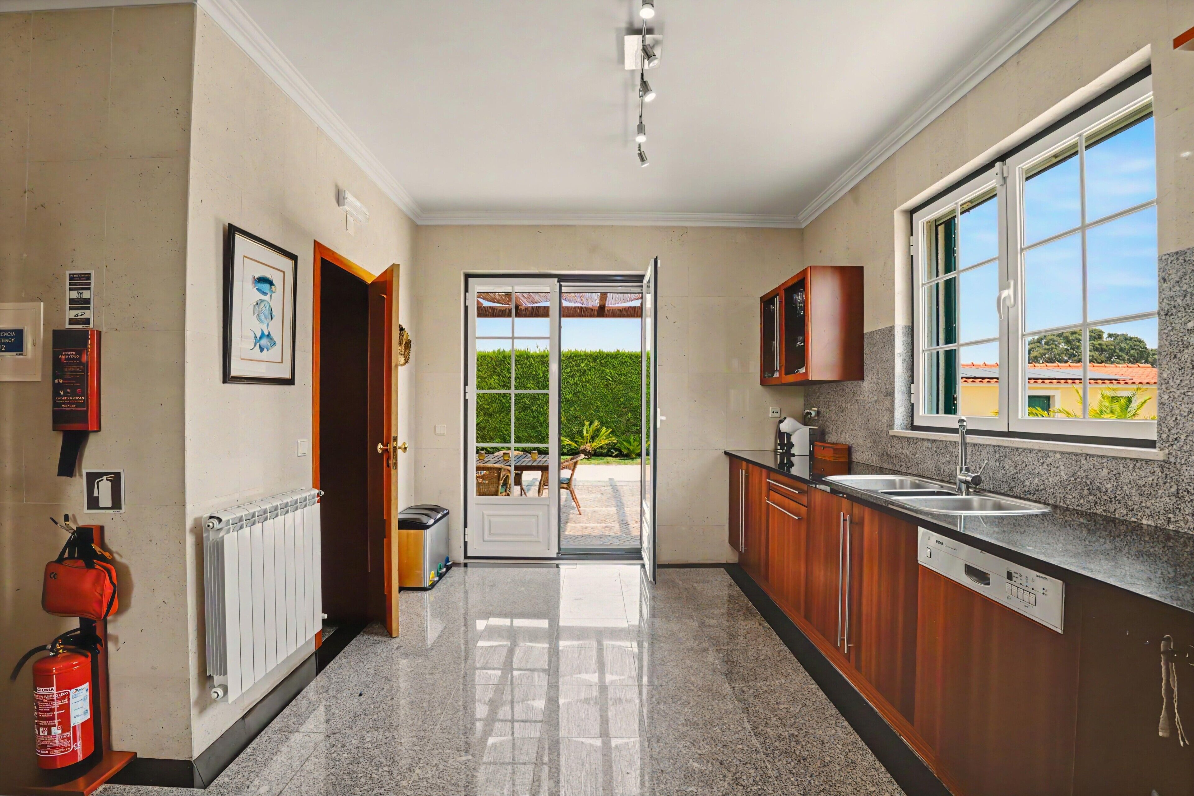 A modern kitchen with a large window, a door leading to a patio, and a fire extinguisher on the wall.