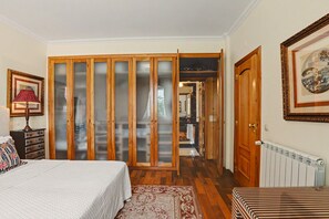 Un dormitorio con cama, cómoda, mesita de noche, lámpara, armario y radiador.