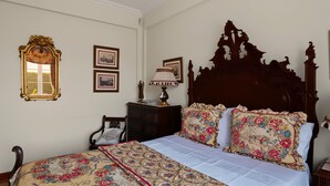 Une chambre à coucher avec un grand lit, une tête de lit décorative et un miroir doté d’un cadre orné.