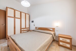 Un dormitorio con cama de madera, mesita de noche, armario y luz en la pared.