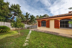 Una casa con techo de tejas, un pequeño jardín con un sendero y una cerca.