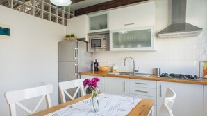 Una cucina moderna con mobili bianchi, un tavolo da pranzo in legno e un vaso con fiori.