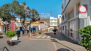 A street with buildings, a pedestrian crossing, and a sign indicating a no parking zone except for authorized vehicles. - Vacation Home "Casa La Palmilla" with Mountain View, Whirlpool & Wi-Fi (La Aldea de San Nicolás)