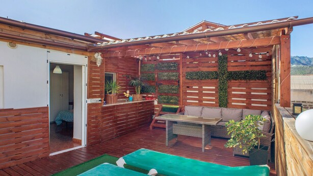 A wooden deck with a sofa, a table, and a bench. - Vacation Home "Casa La Palmilla" with Mountain View, Whirlpool & Wi-Fi (La Aldea de San Nicolás)