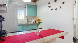 A kitchen with a clock, a vase with flowers, and a red cloth on the table. - Vacation Home "Casa La Palmilla" with Mountain View, Whirlpool & Wi-Fi (La Aldea de San Nicolás)