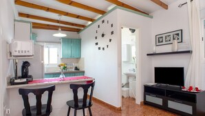 A kitchen with a microwave, a sink, and a clock on the wall. There are two chairs and a TV stand. - Vacation Home "Casa La Palmilla" with Mountain View, Whirlpool & Wi-Fi (La Aldea de San Nicolás)