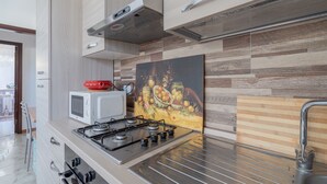 A modern kitchen with a gas stove, microwave, and stainless steel sink. - "Villa Angela" with Terrace, Shared Garden & Wi-Fi (Augusta)