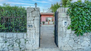 A stone gate leading to a building with a tiled roof, a number plaque, and a small garden area. - "Villa Angela" with Terrace, Shared Garden & Wi-Fi (Augusta)
