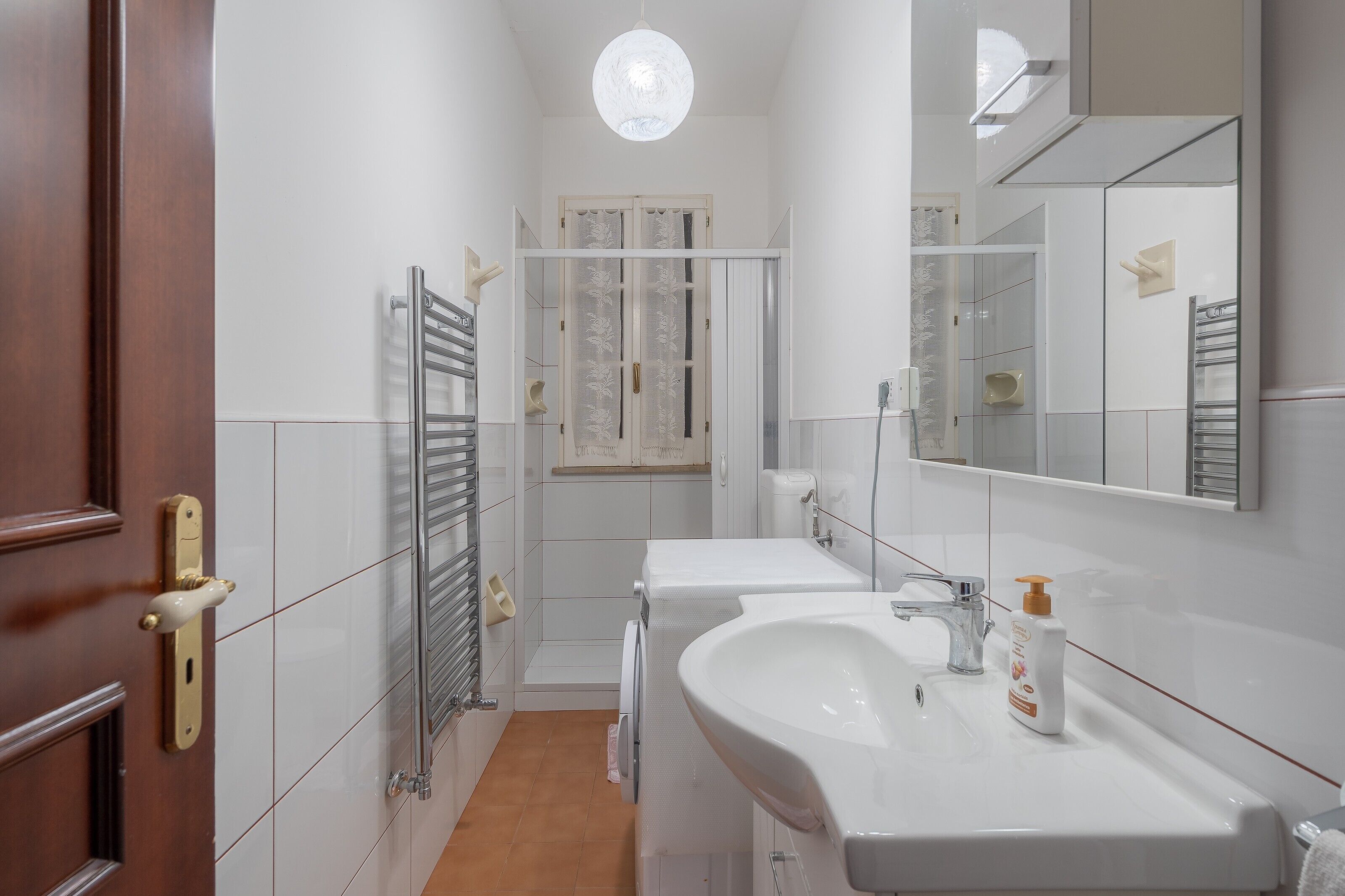 Une salle de bain avec une porte en bois, un porte-serviettes, des toilettes et un lavabo avec un miroir.