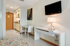 Une chambre d’hôtel comprenant un lit, un bureau avec une chaise, un téléviseur fixé au mur et une lampe.