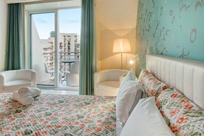 Une chambre d’hôtel avec un lit, deux chaises, une lampe et une vue sur la ville, visible à travers une porte coulissante.