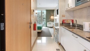 Een hotelkamer met kitchenette, een bed, een badkamer en uitzicht op de stad.