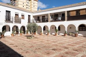 A courtyard with a tiled floor, white walls, and multiple balconies with railings.
