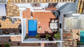 Une terrasse sur le toit avec une piscine, des sièges extérieurs et des plantes en pot.