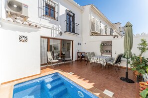 A residential property with a swimming pool, outdoor seating, and a balcony with a view.