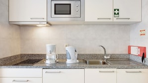 Een keuken met een ingebouwde magnetron, een koffiezetapparaat en een spoelbak.