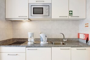 A kitchen with a built-in microwave, a coffee maker, and a sink.