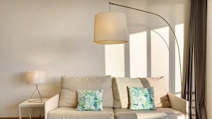 Een moderne woonkamer met een bank, twee kussens met een patroon, een vloerlamp en een tafellamp.
