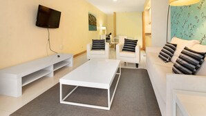 Een moderne woonkamer met een flatscreen televisie, witte banken, een salontafel en een tv-meubel.