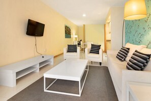 A modern living room with a flat-screen TV, white sofas, a coffee table, and a TV stand.