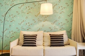 Un sofá con dos almohadas, una lámpara y una pared con diseño.