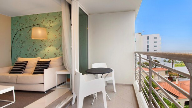 Een balkon met een witte bank, een kleine tafel en een stoel.