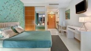 Ein Hotelzimmer mit Bett, Schreibtisch, Fernseher und einem durchgegangenen Tür sichtbaren Badezimmer.