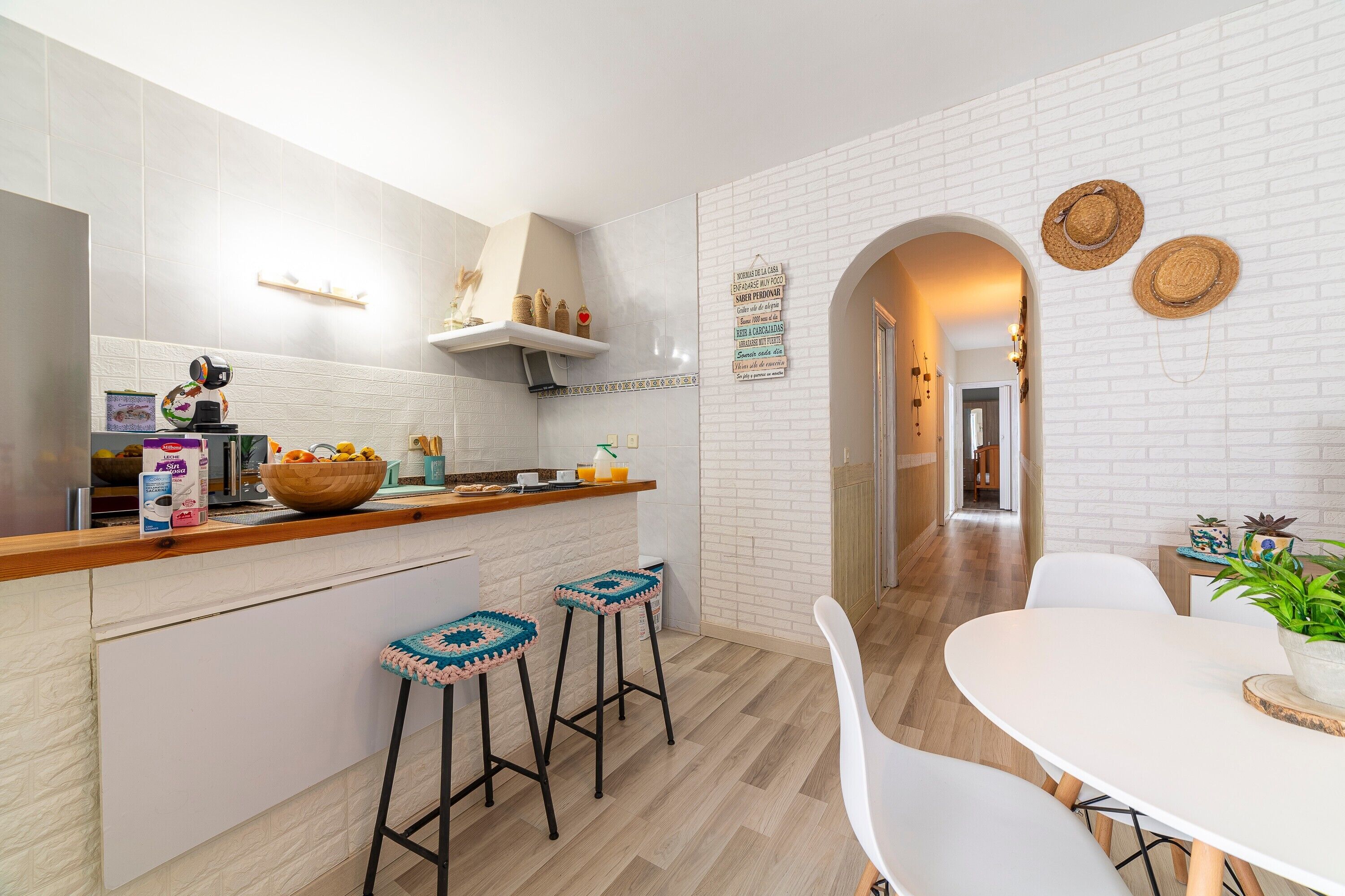 Una cocina moderna con paredes de ladrillo blanco, encimeras de madera y taburetes de bar.
