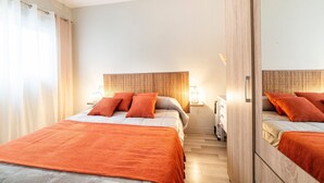 A hotel room with a bed, a bedside table, a lamp, and a mirror.