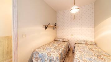 Un dormitorio pequeño con dos camas, una estantería con una lámpara y una pared con diseño de estrellas.