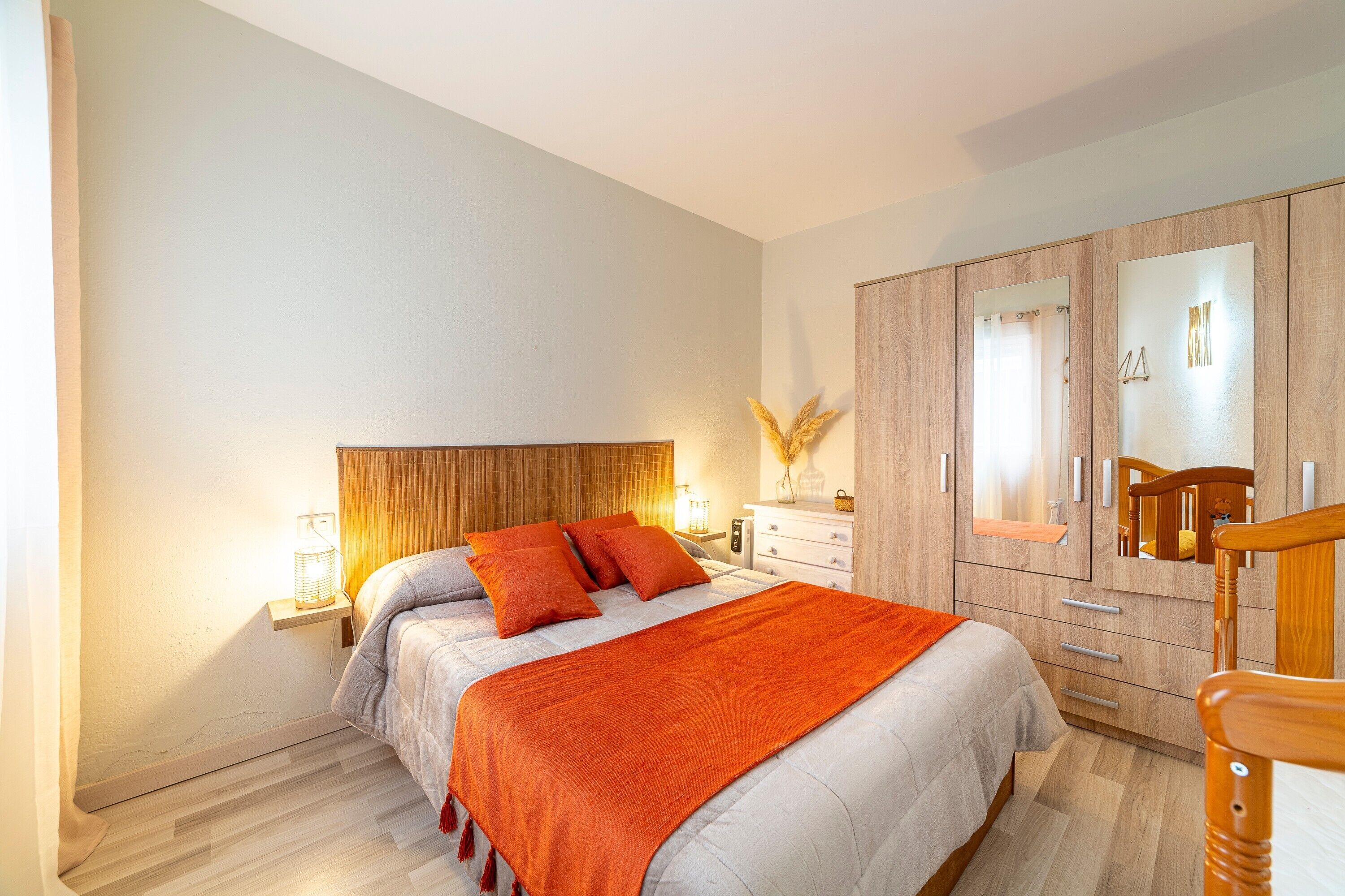 Een slaapkamer met een bed, nachtkastjes, een garderobe en een spiegel.