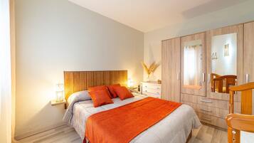 Een slaapkamer met een bed, nachtkastjes, een garderobe en een spiegel.
