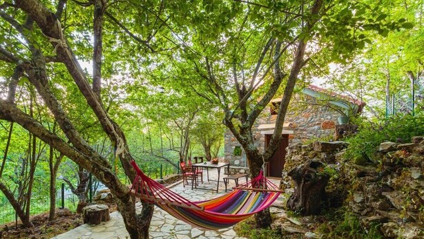 A hammock between trees, stone patio, and rustic stone building. - Pine Forest Chalet 1400m | Cinema & Fireplace (Artemisia)