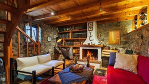 A cozy room with a fireplace, wooden bookshelves, a sofa, and a dining table. - Pine Forest Chalet 1400m | Cinema & Fireplace (Artemisia)