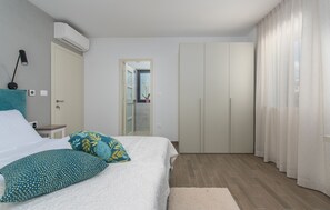 A bedroom with a bed, a nightstand, a wardrobe, and an air conditioning unit.