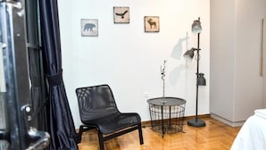 A room with a black leather chair, a small round table, and a floor lamp. There are three wall-mounted pictures depicting animals. - Central apartment at Echarxia 2 beds for 5 pers by MPS (Αθήνα)