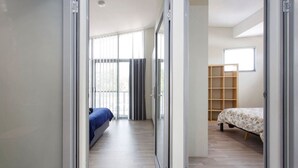 Una habitación con una cama, una estantería de madera y una puerta corredera que da a otra habitación.