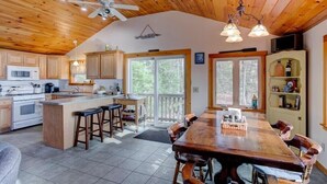A spacious kitchen with wooden cabinets, a large island, and a dining area with a wooden table and chairs. - Winnipesaukee Waterfront Home Sleeping for 8 (Moultonborough)