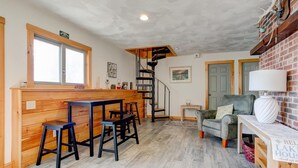 A cozy interior with a wooden bar, a spiral staircase, and a grey sofa. - Winnipesaukee Waterfront Home Sleeping for 8 (Moultonborough)