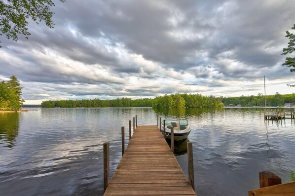 Un muelle de madera que se extiende sobre un lago tranquilo, con un bote amarrado al final.