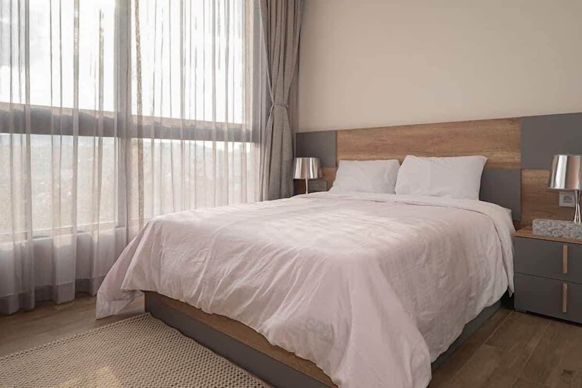 Ein modernes Schlafzimmer mit einem großen Bett, zwei Nachttischen und durchsichtigen Vorhängen.